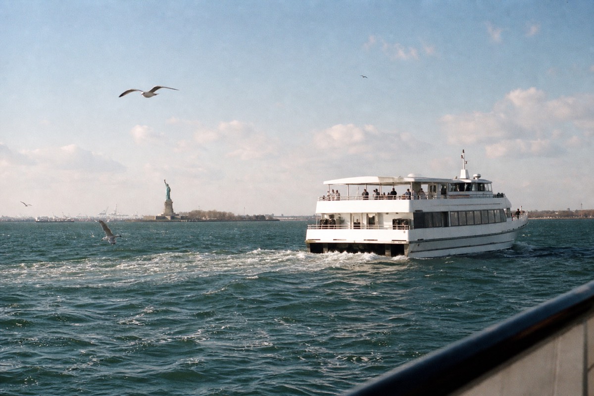 Sightseeing boat crossing New York Harbor with the Statue of Liberty in the distance