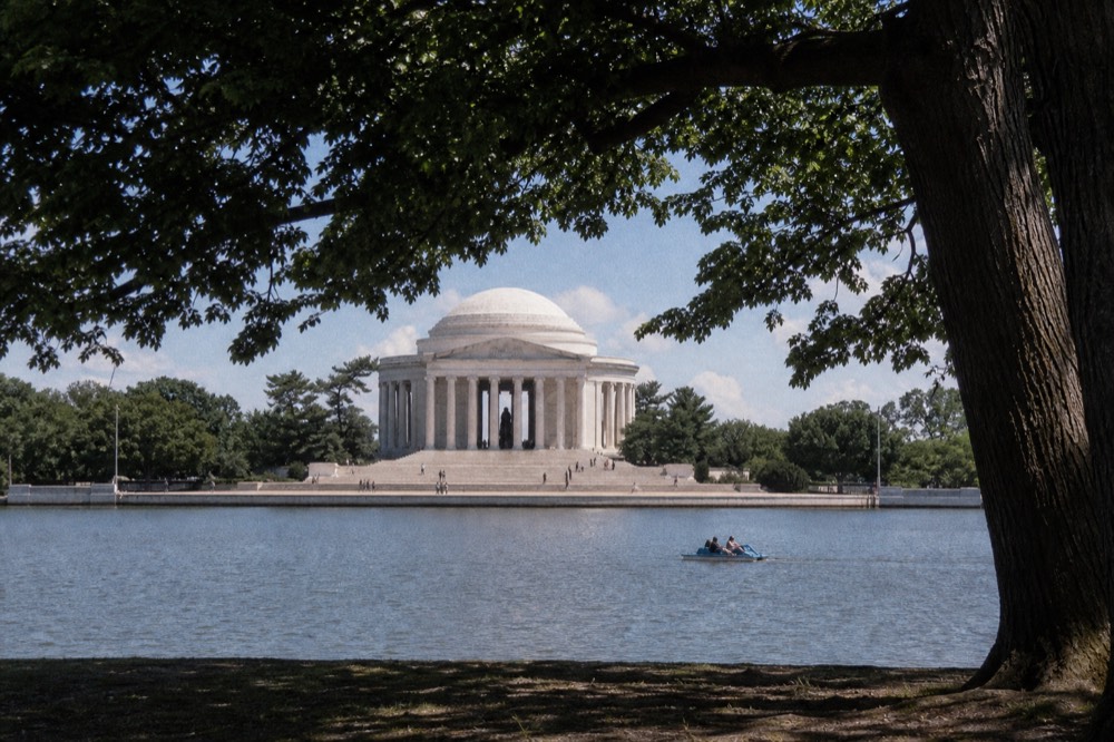 Marble neoclassical dome above a long reflecting pool at midday, bare stone steps in flat white light, distant figures reduced to small dark shapes